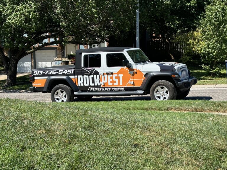 Rock Pest Control branded truck parked on a residential street, showcasing pest management services with contact number visible.