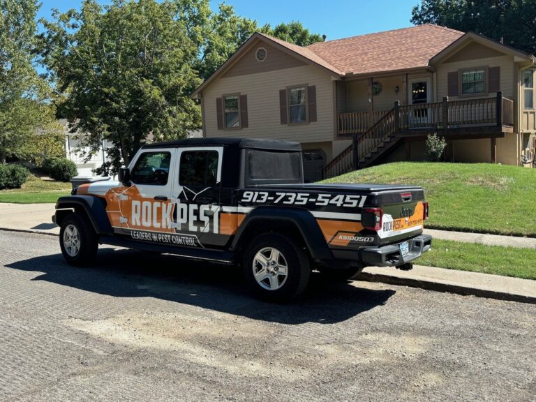 Rock Pest Control service vehicle parked in front of a residential home, featuring the company logo, contact number, and pest control branding.
