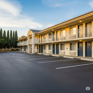 Exterior view of a motel with multiple rooms, featuring a well-maintained parking lot and landscaping, emphasizing the property&rsquo;s suitability for discreet pest control services.